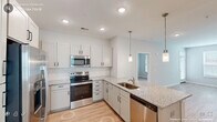 Located at 405 TW Alexander Dr in Durham, NC, this single-floor residence offers three bedrooms, two bathrooms, a combined kitchen and living room, a dedicated dining room, and two closets — all thoughtfully arranged within a well-proportioned floor plan.

The kitchen is a standout feature, outfitted with stainless steel appliances including a range, microwave, and dishwasher, complemented by granite countertops, a undermount sink, and crisp white shaker cabinetry with modern hardware. A peninsula with pendant lighting adds both function and visual interest, while recessed lighting and light wood-style flooring complete the contemporary aesthetic.

The living room benefits from natural light through large windows fitted with blinds, and continues the same light flooring found throughout the home. Each of the three bedrooms is well-sized, with the spacious primary bedroom offering direct access to a private bathroom. Bedrooms feature ceiling fans with integrated lighting, windows for natural light, and easy closet access. The bathrooms are cleanly finished, with one featuring a walk-in glass-enclosed shower with white subway tile surround.

Neutral wall tones, white trim, and consistent flooring create a cohesive, modern atmosphere throughout this Durham residence.