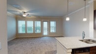 Located at 14940 Mueschke Rd in Cypress, TX, this single-floor residence offers a well-designed layout with quality finishes throughout. The entryway opens to wood-look flooring that flows into a thoughtfully appointed kitchen, which features rich dark wood cabinetry, granite countertops, a tile backsplash, stainless steel appliances including a French door refrigerator, range, and built-in microwave, as well as a double undermount sink with pendant lighting above. Crown molding adds a refined touch throughout the home. The open living area is carpeted and bathed in natural light from multiple windows fitted with blinds, alongside a glass door providing direct access to an outdoor balcony with views of the surrounding greenery. A ceiling fan enhances comfort in this generous living space. The bedroom is carpeted and features a ceiling fan, natural light from a window, and direct access to a private en-suite bathroom. The bathroom is equipped with granite countertops, a glass-enclosed walk-in shower with tile surround, and wood-look flooring. A walk-in closet with wrap-around hanging rods offers ample storage. Additionally, a dedicated laundry area accommodates a full-size washer and dryer, providing convenient in-unit utility.