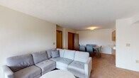 Located at 499 Indian Mound Dr in Mount Sterling, Kentucky, this single-floor residence offers a well-organized layout designed for comfortable everyday living. The open living and dining area serves as the heart of the home, with warm-toned carpeting throughout and neutral walls that create a bright, welcoming atmosphere. The living room is generously proportioned, accommodating a large sectional sofa, and features sliding glass doors fitted with vertical blinds that open to a private balcony, allowing natural light to flow into the space and offering pleasant outdoor views. Adjacent to the living area, the dining space comfortably fits a full six-seat dining table and sits conveniently close to the kitchen. The galley-style kitchen is efficiently designed with ample white cabinetry featuring wood-trimmed accents, generous counter space, a sink, and full-size appliances including a refrigerator and microwave, all set on wood-look flooring. The two bedrooms are carpeted and well-sized, each with windows for natural light and closet storage, including a spacious reach-in closet with wire shelving. The bathroom features wood-look flooring, a full soaking tub and shower combination with a curtain, and a towel bar. The overall ambiance is clean, functional, and move-in ready.