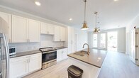 Located at 3612 Beverly Cove Way in Wilmington, NC, this well-appointed 2-bedroom, 2-bathroom single-floor residence offers a thoughtfully designed layout with modern finishes throughout. Light-toned hardwood-style flooring flows seamlessly across the entire space, complemented by crown molding that adds a refined touch to each room.

The open-concept kitchen is a standout feature, showcasing crisp white shaker cabinetry, a classic subway tile backsplash, stainless steel appliances, and a large center island with a quartz-style countertop and an undermount sink. Brushed gold pendant lights and matching faucet hardware lend a warm, contemporary elegance to the space.

The living area opens to a private balcony through glass-paned doors, allowing abundant natural light to pour in. Ceiling fans in the living and bedroom areas provide both comfort and style. The spacious primary bedroom includes a generous walk-in closet with built-in wire shelving. The second bedroom features a wide bank of windows with outdoor views, further brightening the space.

Both bathrooms are finished with neutral tones, dark countertops, and tiled tub-shower combinations with brushed nickel fixtures. A dedicated in-unit laundry room with full-size washer and dryer hookups adds everyday convenience. Two closets and a connected hallway complete the functional, well-organized floor plan.