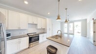 Located at 3612 Beverly Cove Way in Wilmington, NC, this well-appointed 2-bedroom, 2-bathroom single-floor residence offers a thoughtfully designed layout with modern finishes throughout. Light-toned hardwood-style flooring flows seamlessly across the entire space, complemented by crown molding that adds a refined touch to each room.

The open-concept kitchen is a standout feature, showcasing crisp white shaker cabinetry, a classic subway tile backsplash, stainless steel appliances, and a large center island with a quartz-style countertop and an undermount sink. Brushed gold pendant lights and matching faucet hardware lend a warm, contemporary elegance to the space.

The living area opens to a private balcony through glass-paned doors, allowing abundant natural light to pour in. Ceiling fans in the living and bedroom areas provide both comfort and style. The spacious primary bedroom includes a generous walk-in closet with built-in wire shelving. The second bedroom features a wide bank of windows with outdoor views, further brightening the space.

Both bathrooms are finished with neutral tones, dark countertops, and tiled tub-shower combinations with brushed nickel fixtures. A dedicated in-unit laundry room with full-size washer and dryer hookups adds everyday convenience. Two closets and a connected hallway complete the functional, well-organized floor plan.