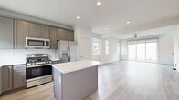This well-appointed two-story home offers 3 bedrooms and 4 bathrooms across two thoughtfully laid-out floors. The main level features an open-concept living and kitchen area bathed in natural light from large sliding glass doors and multiple windows. The kitchen is outfitted with gray shaker-style cabinetry, a white quartz-topped center island, subway tile backsplash, and a full suite of stainless steel appliances including a gas range, built-in microwave, dishwasher, and French door refrigerator. Light wood-look flooring flows seamlessly throughout both levels, complementing the clean, neutral color palette. The living area is generous and airy, anchored by a ceiling fan and direct access to the outdoors. A convenient half bath is also located on the main floor. Upstairs, the primary bedroom offers a comfortable retreat with an en-suite bathroom featuring both a soaking tub and a separate glass-enclosed shower. The additional bedrooms are well-sized with ample natural light and views of the surrounding landscape. A dedicated laundry room with a full-size washer and dryer, a hallway, closet, and additional bathrooms complete the upper level. Recessed lighting and roller shade window treatments are featured throughout.