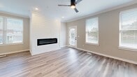 This three-story home in Olathe, Kansas offers a well-designed layout across three distinct levels, totaling generous living space suited for everyday comfort and functionality. The entry-level features an attached garage with automatic door access, providing convenient and secure parking. The main living floor serves as the heart of the home, highlighted by an open-concept kitchen and living area. The kitchen is outfitted with crisp white shaker cabinetry, quartz countertops, stainless steel appliances, a large center island with a deep sink, and stylish pendant lighting — a functional and visually striking space. The adjacent living room features light hardwood-style flooring, crown molding, a ceiling fan, and a standout shiplap accent wall framing a sleek linear fireplace, with natural light streaming in through multiple windows. The upper floor houses the three bedrooms, each equipped with ceiling fans. The generously sized primary bedroom connects directly to an en-suite bathroom featuring a walk-in glass-enclosed shower with tile surround and dual-sink white vanity. Additional bathrooms include a tub-shower combination with matte black fixtures. The walk-in closets offer built-in shelving and hanging rods for ample storage. Consistent light-toned flooring and neutral walls unify the home's clean, contemporary aesthetic throughout.