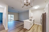 Located at 100 Thompson Farm Rd in Bedford, MA, this thoughtfully designed one-bedroom, one-bathroom residence offers a clean, modern aesthetic throughout its single-floor layout. Warm wood-look flooring flows continuously through every room, tying the space together with a cohesive, contemporary feel.

The open-concept kitchen, dining, and living area forms the heart of the home. The kitchen features white shaker cabinetry, a white quartz peninsula with an undermount sink, subway tile backsplash, and a full suite of stainless steel appliances including a refrigerator, range, and microwave. A geometric chrome chandelier above the peninsula adds an elegant focal point. The living room extends naturally from this space and is anchored by a sliding glass door that invites natural light and provides outdoor access.

The generously sized primary bedroom offers a tranquil retreat with neutral tones, ample wall space, and access to a walk-in closet with wire shelving. Two additional closets provide exceptional storage throughout the unit. A dedicated laundry room houses a full-size Whirlpool washer and dryer.

The bathroom is well-appointed with a white vanity, quartz countertop, lighted mirror, and a subway-tiled soaking tub/shower combination with brushed nickel fixtures. Clean lines and neutral finishes give this residence a polished, move-in-ready appeal.