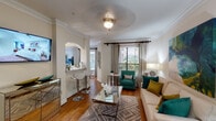 Located in Houston's desirable 77005 zip code, this well-appointed single-floor residence offers a thoughtfully designed layout with refined finishes throughout. The open-concept living area features warm hardwood flooring, crown molding, and large windows that invite abundant natural light. A comfortable seating arrangement anchors the space, complemented by a mirrored coffee table and vibrant teal and gold accent pieces that add a contemporary flair.

The kitchen is equipped with stainless steel appliances, including a refrigerator, range, and microwave, set against a light tile backsplash and granite countertops. A peninsula with bar seating connects the kitchen to the living area through an elegant archway, creating an ideal flow for entertaining. A dedicated dining area with a large window provides a bright, inviting setting for meals.

The bedroom features plush carpeting, crown molding, a ceiling fixture, and a window overlooking greenery, lending a serene atmosphere. The full bathroom includes an extended dual vanity with granite counters, tile flooring, and a shower-tub combination. A dedicated in-unit laundry area with a full-size washer and dryer adds everyday convenience, completing this well-rounded Houston residence.