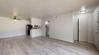 Located at 717 S Green St in Longview, Texas, this single-story 2-bedroom, 1-bathroom home offers a straightforward and functional layout finished with consistent light wood-look luxury vinyl flooring throughout. The spacious living room greets you at the entry, featuring a ceiling fan, textured ceiling, and a large window that allows natural light to filter in, creating a bright and open atmosphere. The kitchen connects directly to a combined dining area and is fitted with white cabinetry, a countertop sink, and black appliances including a full-size refrigerator and range. A peninsula-style counter separates the kitchen from the living space, adding definition to the open floor plan. Both bedrooms are well-proportioned, each equipped with a ceiling fan and a dedicated closet with built-in shelving for organized storage. The primary bedroom offers generous square footage, enhanced by natural light from a large window with blinds. A central hallway connects the bedrooms to the shared full bathroom, which includes a tiled tub/shower combination with grab bars and a clean, white finish. Four total closets throughout the home provide exceptional storage capacity. The neutral color palette and clean finishes create a move-in ready environment suitable for a variety of living arrangements.