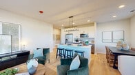Located at 2611 Hopps Rd in Elgin, IL, this thoughtfully designed 2-bedroom, 2-bathroom model home delivers a comfortable and modern living experience on a single floor. The open-concept layout seamlessly connects the living room, dining area, and kitchen, creating a bright and cohesive space anchored by light hardwood flooring throughout. Large windows in the living and dining areas invite abundant natural light and outdoor views, enhancing the airy ambiance.

The kitchen is a standout feature, boasting white shaker upper cabinets, gray lower cabinets, sleek quartz countertops, stainless steel appliances, and a central island with bar seating beneath a statement geometric pendant light. The adjoining dining area is framed by oversized windows overlooking the outdoors.

The generously sized primary bedroom offers plush carpeting, ample natural light, and direct access to a bathroom with a white quartz vanity and a walk-in closet outfitted with wire shelving systems. The second bedroom is equally well-appointed with soft carpet and a bright window. Both bathrooms feature clean, contemporary finishes. Additional conveniences include an in-unit laundry area and a dedicated hallway connecting all rooms efficiently throughout this well-planned home.