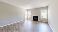 Located at 600 Old Holcomb Bridge Road in Roswell, GA, this one-bedroom, one-bathroom unit offers a well-organized layout across a single floor. The living room is a welcoming centerpiece, featuring a classic wood-burning fireplace framed in sleek black, wood-look laminate flooring, and multiple windows dressed with horizontal blinds that fill the space with generous natural light. A dedicated entryway leads directly into the living area, offering a clean sense of arrival. The kitchen is designed with functionality in mind, showcasing warm honey-toned wood cabinetry, dark countertops, a stainless steel refrigerator, and a raised breakfast bar pass-through that connects to the living and dining area — ideal for casual dining or entertaining. A hallway leads to the private bedroom, a comfortably scaled retreat with wood-look flooring, neutral gray walls, and a closet for storage. The full bathroom is clean and practical, featuring a full-size tub and shower combo with white tile surround, a vanity with dark countertop, and a mirror. Neutral tones, textured ceilings, and consistent flooring throughout lend the unit a cohesive, move-in-ready aesthetic well-suited for comfortable everyday living in the heart of Roswell.