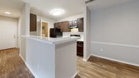 Located at 1207 Kelston Pl in Charlotte, NC, this single-story, 2-bedroom, 1-bathroom home offers a well-organized layout designed for comfortable everyday living. The open-concept living and dining area features wood-look flooring, neutral toned walls, a textured ceiling, and a fireplace that serves as a natural focal point. Sliding glass doors lead to a private balcony, filling the living space with natural light and outdoor views. The kitchen is positioned adjacent to the living area and features dark espresso cabinetry, a light quartz-style countertop with a breakfast bar peninsula, and black appliances including a refrigerator and range. Both bedrooms are carpeted and receive natural light through large windows. The generously sized primary bedroom includes direct access to a closet and the shared bathroom. The full bathroom is finished with a white vanity, mirror, towel bar, and a tub-shower combo. Two closets with wire shelving systems provide practical storage throughout the home. A dedicated utility room adds further functionality. The overall palette of warm neutrals and consistent finishes gives the home a clean, cohesive aesthetic throughout.