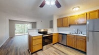 This single-floor, one-bedroom, one-bathroom residence offers a functional and comfortable layout across a compact yet efficient footprint. The open-concept kitchen and living area serves as the heart of the home, featuring warm honey-toned wood cabinetry, stainless steel appliances including a range, dishwasher, and refrigerator, and light-colored countertops. A ceiling fan overhead and durable wood-style flooring throughout the common areas enhance both practicality and style. The living room is bright and airy, benefiting from a large sliding glass door that frames a lush, wooded outdoor view and invites abundant natural light. The spacious primary bedroom is finished with plush carpeting, neutral gray walls, and a window overlooking the surrounding greenery, offering a tranquil retreat. A generously sized walk-in closet with built-in shelving and hanging rods provides ample storage. The bathroom is clean and functional, equipped with a full tub-and-shower combination surrounded by classic white tile. A hallway connects the living spaces to the private quarters, completing this efficiently designed home. Textured ceilings are consistent throughout the unit.