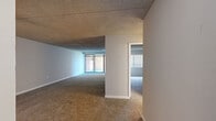 This single-floor residence offers a practical and comfortable layout across two bedrooms, one bathroom, a kitchen, hallway, and closet. The open living area is generously proportioned, featuring wall-to-wall carpeting and a textured ceiling throughout. Large sliding glass doors at the far end of the living space allow natural light to flood in, creating a bright and airy atmosphere. A central partial wall divides the space while maintaining an open feel, with a secondary room visible beyond it, also benefiting from natural light through a window with blinds.

The kitchen is well-equipped with white cabinetry extending to the ceiling, light granite-style countertops, a stainless steel sink, and a white gas range. Light wood-look vinyl flooring adds a clean, modern touch to this functional cooking space.

The primary bedroom is notably expansive, offering generous square footage with soft carpeting, neutral grey walls, and a ceiling fan overhead. The second bedroom is comfortably sized with a window that brings in natural light and direct access to a closet with built-in shelving. The full bathroom features a clean, all-white aesthetic with a shower/tub combo, toilet, and vanity, complemented by matching light wood-look vinyl flooring.