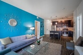 Located at 146 Old Country Road in Mineola, NY, this single-floor residence showcases a thoughtfully designed open-concept layout with contemporary finishes throughout. The kitchen serves as a central focal point, featuring dark espresso cabinetry, stainless steel appliances, a subway tile backsplash, and a large island with a dark countertop and bar seating — ideal for both everyday cooking and casual dining. Hardwood-style flooring runs through the main living areas, anchoring the cohesive aesthetic.

The living room is bright and inviting, benefiting from large windows and a glass door that invite abundant natural light and views of the surrounding exterior. A bold teal accent wall adds a striking visual element, complemented by a neutral sofa, glass coffee table, and a textured area rug.

The bedrooms are carpeted for comfort and feature distinctive accent walls — including rich plum and warm gold tones — that lend each room a unique character. Ample space accommodates full bedroom furnishings alongside decorative elements. The bathrooms offer dark-finished vanities with framed mirrors, illuminated vanity lighting, and wood-style flooring, providing a polished, modern feel throughout.