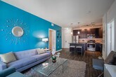 Located at 146 Old Country Road in Mineola, NY, this single-floor residence showcases a thoughtfully designed open-concept layout with contemporary finishes throughout. The kitchen serves as a central focal point, featuring dark espresso cabinetry, stainless steel appliances, a subway tile backsplash, and a large island with a dark countertop and bar seating — ideal for both everyday cooking and casual dining. Hardwood-style flooring runs through the main living areas, anchoring the cohesive aesthetic.

The living room is bright and inviting, benefiting from large windows and a glass door that invite abundant natural light and views of the surrounding exterior. A bold teal accent wall adds a striking visual element, complemented by a neutral sofa, glass coffee table, and a textured area rug.

The bedrooms are carpeted for comfort and feature distinctive accent walls — including rich plum and warm gold tones — that lend each room a unique character. Ample space accommodates full bedroom furnishings alongside decorative elements. The bathrooms offer dark-finished vanities with framed mirrors, illuminated vanity lighting, and wood-style flooring, providing a polished, modern feel throughout.