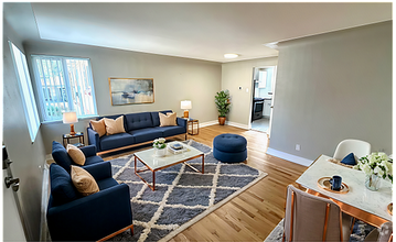Chic and cozy apartment featuring a bright living area with plush seating and modern decor. Hardwood floors and large windows create an inviting atmosphere in this 1 bed, 1 bath unit for $1,350 per month. - Flats at 16th