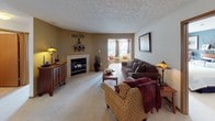 Located at 1302 Hemmingway Dr. in Fairborn, Ohio, this single-floor home offers a well-designed layout with a comfortable and functional living experience. The living room serves as the heart of the home, centered around a gas fireplace and finished with plush carpeting and a textured ceiling. Natural light filters in through windows, creating a warm and inviting atmosphere. An adjacent sunroom or sitting area extends the living space further. The dining area accommodates a full-sized table and connects seamlessly to the kitchen through a pass-through window, enhancing the open feel. The kitchen features wood cabinetry, a full suite of appliances including a range, over-the-range microwave, and refrigerator, along with durable laminate flooring. The bedrooms are generously sized, each with carpeted floors, ample natural light from large windows, and neutral-toned walls. Two full bathrooms include oak vanity cabinetry, single-sink countertops, and tub-shower combinations. A dedicated laundry room with overhead cabinetry accommodates a full-size washer and dryer, adding everyday convenience to this well-appointed home.