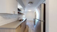 Located at 11141 Springhollow Rd in Oklahoma City, Oklahoma, this single-floor residence offers a clean, contemporary design with thoughtful updates throughout. The galley-style kitchen is a standout feature, showcasing two-tone cabinetry with white upper cabinets and warm wood-tone lower cabinets, white subway tile backsplash, quartz-style countertops, and a full suite of stainless steel appliances including a refrigerator, electric range, microwave, and dishwasher. Open shelving adds a modern touch, while wood-look luxury vinyl plank flooring runs consistently throughout the home, lending warmth and visual continuity. The living area is open and airy, benefiting from natural light through sliding glass doors that provide outdoor access. A fireplace with a clean surround serves as a focal point in one of the main living spaces, which also features a louvered bi-fold closet for added storage. The bedroom is well-proportioned with a ceiling fan, a window with blinds for natural light, and neutral gray walls that complement the light flooring. The bathroom includes a tub-shower combination with brushed nickel fixtures and a clean white finish. Throughout the home, crisp white trim, neutral wall tones, and consistent flooring create a cohesive, move-in-ready aesthetic.