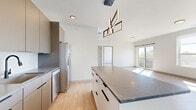 This contemporary 2-bedroom, 2-bathroom residence at 1851 Brevier Avenue in Cleveland, Ohio offers a thoughtfully designed single-floor layout with modern finishes throughout. Light wood-tone flooring flows seamlessly across the entire space, complementing the crisp white walls and creating a clean, cohesive aesthetic.

The open-concept living, dining, and kitchen area serves as the heart of the home. The kitchen is well-appointed with sleek taupe flat-front cabinetry extending to the ceiling, stainless steel appliances, a subway tile backsplash, granite-style countertops, and a central island with additional storage. A striking geometric pendant light anchors the kitchen space. The living area is generously proportioned and bathed in natural light, with sliding glass doors opening to a private balcony offering elevated views of the surrounding greenery and neighborhood.

Both bedrooms are comfortably sized, featuring large windows that bring in abundant sunlight and tree-lined views. The primary bedroom benefits from expansive floor-to-ceiling windows providing panoramic outdoor vistas. Three closets, including a walk-in with built-in wire shelving, provide ample storage throughout.

The two bathrooms are finished in a modern style with floating gray vanities, white countertops, round mirrors, and matte black hardware accents. A dedicated laundry area and additional closet storage complete this well-appointed residence.