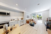 Located at 2650 41st Avenue East in Vancouver, BC, this one-bedroom, one-bathroom unit offers a thoughtfully designed layout across a single floor. The space features a clean, contemporary aesthetic throughout, with light-toned finishes and an efficient use of space.

The modern kitchen is well-appointed with light grey cabinetry extending to the ceiling, white tile backsplash, white quartz countertops, and a full suite of stainless steel appliances including a refrigerator, electric range, microwave, and dishwasher. A compact dining table with bar-height seating sits adjacent to the kitchen, making it ideal for casual meals.

The living room is bright and inviting, benefiting from large windows and a sliding glass door that opens directly to an outdoor patio, allowing natural light to pour in and providing greenery views of the surrounding neighbourhood. Light hardwood flooring flows through the main living areas, enhancing the airy feel of the space.

The bedroom is a calm, comfortable retreat with a ceiling fan, carpeted flooring, and a window that frames views of the outdoors. A dedicated closet provides practical storage.

The bathroom is finished with large-format light grey tiles, a soaker tub with shower, and clean white fixtures, maintaining the unit's consistent modern and minimal aesthetic throughout.