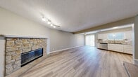 This two-story home in Olathe, Kansas offers a well-designed layout with 2 bedrooms and 1.5 bathrooms across a generously sized floor plan. The main level features an open-concept living and kitchen area with light hardwood-style flooring throughout. The kitchen is outfitted with white cabinetry, granite countertops, a mosaic tile backsplash, and a full suite of stainless steel appliances including a range, microwave, dishwasher, and refrigerator. A sliding glass door off the kitchen and living area provides access to the exterior and fills the space with natural light. The living room showcases a striking stone-surround fireplace and vaulted ceiling detail, adding warmth and character. A convenient half bathroom on the main level features a vessel sink, granite vanity, mosaic tile backsplash, and a modern round LED mirror. The staircase, accented with wood treads and iron balusters, leads to the upper level where the bedrooms are located. Each bedroom features plush carpeting, a ceiling fan, natural light from windows with blinds, and closet storage. The full bathroom upstairs includes a tub/shower combination with large-format marble-style tile surround. Textured ceilings and neutral wall tones complete the cohesive, move-in-ready aesthetic throughout.