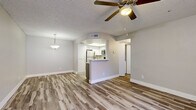 Located in Gilbert, AZ, this single-floor, 3-bedroom, 2-bathroom residence offers a practical and modern layout designed for comfortable everyday living. The open-concept living, dining, and kitchen area forms the heart of the home, featuring light wood-look luxury vinyl flooring, neutral gray walls, and a textured ceiling. A ceiling fan with integrated lighting anchors the living room, while a stylish pendant light illuminates the adjacent dining area. The kitchen is equipped with stainless steel appliances—including a refrigerator, range, and microwave—complemented by two-tone cabinetry in white and gray, white quartz countertops, and a peninsula with a single-basin sink that opens toward the main living space. Each of the three bedrooms offers plush carpeting, natural light through vertical-blind-fitted windows, and ceiling fans in select rooms. The primary bedroom provides a comfortable, well-proportioned retreat. Both bathrooms feature wood-look flooring, tub-shower combinations, and modern vanities with understated cabinetry. A hallway connects the private quarters to the main living areas, with a dedicated closet providing additional storage. The overall aesthetic is clean, contemporary, and move-in ready.