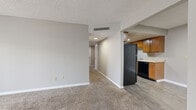 Located at 1311 Greenland Dr in Murfreesboro, TN, this single-floor unit offers two bedrooms and two full bathrooms within a well-organized layout. The entrance opens into a carpeted living area with neutral gray walls, a textured ceiling, and a central HVAC vent, providing a clean and functional common space. Adjacent to the living area, the galley-style kitchen features warm honey-toned wood cabinetry lining both walls, light countertops, a double sink, and durable wood-look vinyl plank flooring, along with black appliances including a full-size refrigerator and dishwasher. A hallway connects the living area to the private quarters, which include two carpeted bedrooms. The generously sized primary bedroom offers notable floor space, while the secondary bedroom features a window with blinds allowing natural light. A sliding glass door with vertical blinds in one of the rooms adds additional light and access. Both bathrooms are equipped with wood-vanity cabinetry, white countertops, large mirrors, and wood-look vinyl flooring, maintaining a consistent design throughout. A closet provides additional storage, completing this straightforward and efficiently arranged home.