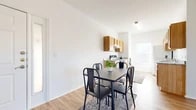 This single-floor unit presents a clean, minimalist design throughout, unified by warm wood-look vinyl flooring and crisp white walls that create a bright, cohesive atmosphere. Natural light filters in through multiple windows fitted with horizontal blinds, enhancing the open feel of each room.

The entryway greets residents with a full-lite door alongside an adjacent window, allowing ample natural light into the foyer. The galley-style kitchen is well-appointed with light oak cabinetry, granite-look countertops, a stainless steel sink, and an electric range, with upper and lower cabinets providing generous storage. A window at the end of the kitchen brings in additional natural light. The kitchen flows directly into the dining area, which comfortably accommodates a four-person dining set.

The living area features a ceiling fan with light fixture and a window offering outdoor views. Multiple bedrooms are present, each with wood-look flooring, white walls, and dedicated closets with wire shelving. One bedroom includes direct access to a bathroom, functioning as a private en suite.

The unit includes two full bathrooms, both featuring light oak vanity cabinetry, granite-look countertops, and wood-look flooring. One bathroom includes a shower-tub combination with a curtain rod, while the other features a soaking tub. The overall ambiance is clean, functional, and move-in ready.