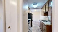 Located at 3000 MN-100 S in St. Louis Park, Minnesota, this one-bedroom, one-bathroom unit offers a practical and comfortable single-floor layout. The galley-style kitchen features warm wood cabinetry, light countertops, wood-look flooring, a stainless steel dishwasher, and a full-size refrigerator, with a functional flow leading into the rest of the unit. The open living area is generously sized, bathed in natural light through a wide multi-pane window that frames treetop views, and is finished with soft grey carpeting that transitions to wood-look flooring near the kitchen. The bedroom is a comfortable, well-proportioned space with its own window offering natural light and outdoor views, plush carpeting, and a wide bifold closet providing ample storage. Hallways connect the rooms efficiently, adding to the unit's organized layout. The bathroom is cleanly finished with tile flooring, a wood-toned vanity with a white countertop, a framed mirror, and a stylish multi-bulb light fixture, creating a bright and functional space. The entrance provides a welcoming introduction to the unit. Overall, the space presents a clean, neutral palette throughout, making it a versatile and move-in ready home.