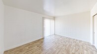 This efficiently designed two-bedroom, one-bathroom unit in Phoenix, Arizona offers a thoughtfully arranged single-floor layout. Throughout the space, light wood-look flooring creates a warm, cohesive feel, complemented by crisp white walls and abundant natural light.

The spacious primary bedroom features white-painted brick walls that add a subtle textural character, a sliding double-door closet, and a large sliding glass door dressed with vertical blinds that invite natural light while providing outdoor access. The second bedroom also showcases the same brick-textured walls, a window with blinds overlooking the exterior, and direct access to the hallway.

The kitchen is outfitted with granite countertops, white cabinetry, and full-size appliances including a refrigerator, providing a clean and functional workspace. A connecting hallway links the kitchen to the living areas, maintaining a practical flow throughout the unit.

The bathroom is well-appointed with a granite-topped vanity, a full-size soaking tub and shower combo with built-in shelving, and a small window that brings in natural light. A ceiling fan in the living area adds comfort suited to Phoenix's warm climate. Overall, the unit presents a clean, updated interior with consistent finishes that create a bright and welcoming atmosphere.