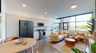 Located at 309 E 15th St in Vancouver, Washington, this contemporary single-floor unit offers a thoughtfully designed open-concept layout with clean lines and modern finishes. The living and kitchen areas flow seamlessly together, bathed in abundant natural light from expansive floor-to-ceiling windows that frame views of the surrounding cityscape. The kitchen is outfitted with stainless steel appliances including a gas range, built-in microwave, and dishwasher, complemented by light wood cabinetry, a hexagonal tile backsplash, and open shelving for added functionality. The living area provides a comfortable and inviting atmosphere with large windows offering elevated outdoor views. The bedroom is a calm retreat featuring neutral tones, a closet with built-in organization, and a window that brings in natural light. A hallway nook with built-in shelving adds practical storage and display space, with an in-unit stacked washer and dryer conveniently nearby. The bathroom features a soaking tub with striking two-tone hexagonal tile surround and matte black fixtures, adding a bold design element. Polished concrete-style flooring runs throughout, tying the modern aesthetic together cohesively.