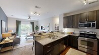 Located at 927 W Morgan St in Raleigh, NC, this single-floor, 3-bedroom, 2-bathroom residence offers a well-designed open layout that maximizes functionality and comfort. The kitchen is a standout feature, equipped with stainless steel appliances including a refrigerator, range, and microwave, complemented by rich dark wood cabinetry, granite countertops, and hardwood-style flooring. A peninsula with bar seating and a bold navy accent wall creates a seamless transition into the living and dining area. The living room is bright and inviting, with access to an outdoor balcony, a ceiling fan, and large windows that bring in natural light. A striking navy accent wall adds depth and character to the space. The generously sized primary bedroom features a soft carpet floor and a sage green accent wall, creating a calm, restful atmosphere. Closets throughout the home are outfitted with wire shelving systems for organized storage. The bathrooms are finished with granite-topped dark wood vanities, tile flooring, and tub-shower combinations with tile surrounds. Neutral tones and consistent finishes throughout the home create a cohesive and modern aesthetic, making this Raleigh residence both practical and stylish.
