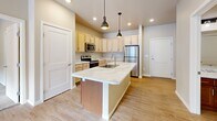 Located at 7911 Hinckley Rd in Baxter, Minnesota, this thoughtfully designed two-bedroom, two-bathroom residence offers a comfortable and modern single-floor layout. The open-concept kitchen serves as the heart of the home, anchored by a large central island with striking marble-look countertops and an undermount sink, illuminated by stylish industrial pendant lighting. Light maple cabinetry, stainless steel appliances — including a refrigerator, range, and microwave — and recessed lighting complete the kitchen's clean, functional aesthetic. The kitchen flows seamlessly into the living area, which features wood-look flooring and a sliding glass door that brings in natural light. Both bedrooms are carpeted and bright, with windows fitted with roller shades. The primary bedroom includes a walk-in closet with wire shelving for ample storage. The two bathrooms are outfitted with warm wood-tone vanities and marble-look countertops; one bathroom features a tub-shower combination. A dedicated in-unit laundry room with full-size washer and dryer adds everyday convenience. Additional wire shelving throughout and a second closet further enhance storage throughout this well-appointed home.