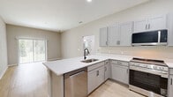 Located at 5790 Stockport St in Riverview, FL, this single-floor, 2-bedroom, 1-bathroom residence offers a clean, modern aesthetic throughout. Light wood-style flooring flows consistently across all rooms, complemented by neutral greige walls and crisp white trim, creating a bright and cohesive interior.

The combined kitchen and living area serves as the heart of the home. The kitchen is well-appointed with gray shaker-style cabinetry, white countertops, and a full suite of stainless steel appliances including a gas range, over-the-range microwave, and refrigerator. The adjacent living room features a sliding glass door fitted with vertical blinds, providing direct outdoor access and filling the space with natural light.

Both bedrooms are comfortably sized, each featuring a ceiling fan, windows with blinds for natural light, and bi-fold closet doors offering generous storage. The primary bedroom is a well-proportioned retreat with ample room for furnishings.

The full bathroom is finished with gray vanity cabinetry, a white countertop, a large mirror, and a walk-in shower enclosed by a sleek black-framed glass door. A hallway connects the main living areas to the bedrooms and bathroom, ensuring a practical and efficient layout throughout this well-maintained Riverview residence.