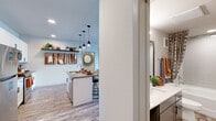 Located at 1561 Brayden Pt in Colorado Springs, CO, this single-story residence offers two bedrooms and two full bathrooms within a thoughtfully designed floor plan. The entrance leads into a kitchen featuring stainless steel appliances, white cabinetry, a peninsula with pendant lighting, and open shelving — flowing seamlessly into the living area. The living room provides access to an outdoor balcony through a glass door, allowing natural light to fill the space. Wood-look plank flooring extends throughout the main living areas, complementing the neutral color palette. The spacious primary bedroom includes a ceiling fan, plush carpet, and a walk-in closet, while the en-suite bathroom offers a double-sink vanity with white quartz countertops and a separate shower. The second bedroom features large windows and soft carpet. The second bathroom includes a soaking tub, tiled surround, and a wide vanity. A stacked washer and dryer unit is conveniently integrated within the unit. Recessed lighting and modern fixtures contribute to a clean, contemporary ambiance throughout.
