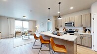 Located at 4455 30th Ave S in Fargo, ND, this well-appointed 2-bedroom, 2-bathroom residence offers a thoughtfully designed single-floor layout with a seamless blend of modern style and everyday functionality. The open-concept kitchen and living area serves as the heart of the home, featuring light wood-tone cabinetry with matte black hardware, a spacious waterfall-edge peninsula with bar seating for two, pendant lighting, and a full suite of stainless steel appliances. A dedicated pantry provides additional storage, while light hardwood-style flooring flows throughout the main living areas. The living room is bright and welcoming, with a large window that fills the space with natural light and offers views of the surrounding neighborhood. Both bedrooms are generously proportioned, with the primary bedroom offering a large closet, plush carpeting, and ample natural light. The two bathrooms are cleanly finished with wood-tone vanities and hardwood-style floors. Additional highlights include a private balcony, a dedicated laundry room with wire shelving, two closets, a utility room, and a neutral color palette that lends a calm, contemporary ambiance throughout.