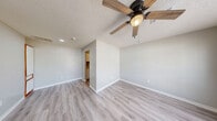 This one-bedroom, one-bathroom unit is thoughtfully laid out to maximize every square foot of available space. Light-toned luxury vinyl plank flooring runs consistently throughout, lending a clean, cohesive aesthetic to the entire floor plan.

The living room serves as the main gathering area, featuring a ceiling fan with integrated lighting, a textured ceiling, and large windows fitted with blinds that allow ample natural light while maintaining privacy. The front entry door opens directly into this bright, open area.

The bedroom is a comfortable, well-proportioned space with its own large window offering views of the surrounding greenery. The room continues the same flooring and neutral wall tones found throughout the unit.

The kitchen is efficiently designed with a dual-basin stainless steel sink, gas range, full-size refrigerator, and a combination of white lower cabinets and wood-trimmed upper cabinets providing generous storage. Light laminate countertops complete the workspace.

The bathroom features a tub-shower combination with tiled surround, a white vanity with mirror, and accessibility grab bars installed at both the tub and toilet. The same light vinyl plank flooring ties the room together with the rest of the unit.

Neutral gray-beige walls and consistent finishes throughout create a calm, move-in-ready atmosphere.