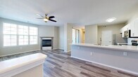 Located at 1862 Denver West Ct in Lakewood, Colorado, this two-story residence offers a thoughtfully designed layout spread across two levels. The main floor features an open-concept living and dining area anchored by wood-look plank flooring and a ceiling fan overhead. A fireplace with a classic gray surround and mantel serves as a focal point in the living area, complemented by large windows fitted with plantation-style shutters that allow generous natural light to fill the space.

The kitchen is well-appointed with two-tone cabinetry — white upper cabinets paired with gray lower cabinets — stainless steel appliances including a refrigerator, range, and built-in microwave, white quartz countertops, a tile backsplash, and a peninsula with an integrated sink that opens to the living area. A half bathroom on the main level features a white vanity with clean-lined cabinetry and wood-look flooring.

Upstairs, the bedrooms feature plush carpeting, ceiling fans, and windows with neighborhood views. The primary bedroom includes access to a walk-in closet. Throughout, the neutral color palette and consistent finishes create a cohesive, move-in-ready environment.