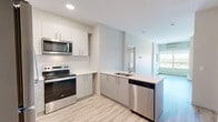 Located at 11025 26 Avenue Northwest in Edmonton, Alberta, this well-appointed 2-bedroom, 2-bathroom unit offers a thoughtfully designed single-floor layout with modern finishes throughout. Light wood-look flooring runs continuously across the living spaces, creating a bright, cohesive aesthetic.

The kitchen is a functional highlight, featuring crisp white upper cabinetry, light grey lower cabinets, quartz countertops, a peninsula with an integrated sink, and a full suite of stainless steel appliances including a refrigerator, electric range, and over-the-range microwave. Recessed lighting adds a polished touch overhead.

Both bedrooms are comfortably sized, each with large windows that invite ample natural light and offer views of the surrounding Edmonton cityscape. The primary bedroom benefits from a built-in closet with double doors, providing practical storage. Baseboard heating is present in both rooms.

The two bathrooms are finished with striking marble-effect wall tiles. The main bathroom features a soaker tub with a curved shower rod, while the second bathroom includes a walk-in shower with a glass door, a grey vanity with quartz countertop, and an illuminated mirror. Clean white walls and wood-look tile flooring complete the modern, neutral palette throughout this well-finished unit.