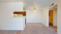 This efficiently designed 1-bedroom, 1-bathroom unit offers a practical and functional layout across a single floor. The combined living and dining area is carpeted in neutral tones, creating a cohesive and comfortable atmosphere. A pass-through counter with an overhead cabinet connects this open area to the kitchen, providing both visual openness and casual dining convenience. The galley-style kitchen is a standout feature, lined on both sides with warm wood-toned cabinetry, ample counter space, and white appliances including a refrigerator, electric range, and dishwasher. Light hardwood-style flooring runs the length of the kitchen, contrasting nicely with the carpeted living areas. The bedroom offers a comfortable footprint, featuring plush carpet, a ceiling fan, and a window dressed with blinds that allows for natural light. A dedicated closet provides storage, while an additional hallway closet adds further functionality. The bathroom is clean and straightforward, equipped with a full soaking tub and shower surround clad in classic white tile, complemented by wood-toned overhead cabinetry. Textured ceilings are consistent throughout the unit, adding a traditional finish to this well-organized and practical living space.