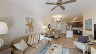 Located at 20 Pine Hall Dr in Clayton, NC, this single-floor residence offers a well-designed open-concept layout that seamlessly connects the living, dining, and kitchen areas. The living room features crown molding, a ceiling fan, and warm neutral tones throughout, creating a bright and inviting atmosphere with abundant natural light filtering through the windows. The kitchen is a standout feature, showcasing rich dark cabinetry, light granite countertops, stainless steel appliances including a refrigerator with ice maker, electric range, and built-in microwave, along with a large center island with an undermount sink and elegant pendant lighting overhead. The dining area flows naturally from both the kitchen and living room, completing the open living space. The bedrooms are comfortable and airy, each equipped with ceiling fans and plush carpeting. One bedroom benefits from multiple windows offering generous natural light. The walk-in closet provides ample storage with wire shelving throughout. The bathrooms are finished with dark wood vanities, granite countertops, large mirrors with modern lighting, and tub/shower combinations, all set on light hardwood-style flooring that ties the home's aesthetic together cohesively.