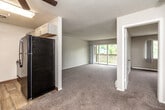This single-floor residence is designed with a practical, functional layout that makes efficient use of its space. The living area serves as the central gathering space, finished with neutral-toned carpeting and bathed in natural light through a large sliding glass door that opens directly onto a private balcony. The balcony overlooks a lush, tree-lined outdoor setting, enhancing the overall sense of openness. A ceiling fan is installed overhead, and baseboard heating runs along the walls throughout the unit.

The galley-style kitchen is efficiently configured, featuring gray shaker-style cabinetry, light granite-look countertops, a double stainless steel sink, and wood-look vinyl plank flooring. It is equipped with a stainless steel refrigerator, an electric range, and a dishwasher.

The bedrooms are carpeted and generously proportioned, each offering ample wall space. One bedroom includes a walk-in closet with shelving, while a large window frames outdoor greenery, filling the room with natural light. Baseboard heaters are present in each bedroom.

The bathroom features wood-look vinyl plank flooring, a white vanity with storage below, a wall-mounted light fixture with a mirror, and a full tub-shower combination.