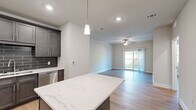 Located at 1210 E Olive Rd in Pensacola, FL, this thoughtfully designed one-bedroom, two-bathroom residence offers a modern and efficient single-floor layout. The open-concept kitchen and living area serves as the heart of the home, anchored by a striking quartz-topped island with pendant lighting overhead. The kitchen is outfitted with dark-toned cabinetry, a complementary subway tile backsplash, and a full suite of stainless steel appliances, including a refrigerator, range, microwave, and dishwasher. Light wood-style flooring flows seamlessly throughout the space, enhancing the bright, airy ambiance. The living room is generously proportioned, featuring a ceiling fan and sliding glass doors that open to a private balcony with outdoor views, filling the room with natural light. The primary bedroom is a comfortable retreat with soft neutral walls and direct access to a dedicated closet outfitted with wire shelving systems for versatile storage. The bathroom includes a full tub-shower combination with built-in shelving and a dark-cabineted vanity with a white countertop and large mirror. The clean, neutral palette and modern finishes throughout create a cohesive and move-in-ready living environment.