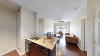 Located at 2505 Longview Street in Austin, TX, this four-bedroom, three-bathroom residence offers a well-designed single-floor layout ideal for shared or family living. The open-concept kitchen and living area serves as the heart of the home, featuring dark cabinetry, stainless steel appliances including a refrigerator, microwave, and range, a breakfast bar with seating, and light stone countertops. The kitchen flows seamlessly into the living room, which is highlighted by rich hardwood flooring, a ceiling fan, and a large sliding glass door that opens onto a private balcony with open outdoor views. The bedrooms are carpeted for comfort and each includes a ceiling fan, natural light from windows with blinds, and a dedicated closet. The primary bedroom offers a generous layout with ample space for study and rest. Three full bathrooms each feature white subway-tiled tub and shower combinations with brushed nickel fixtures and dark cabinetry. A central hallway connects the rooms efficiently, and four closets throughout the unit provide substantial storage. The neutral color palette, clean lines, and consistent finishes create a cohesive and functional living environment throughout the space.