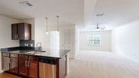 Located at 1001 Aventine Dr in Arden, NC, this single-floor, 3-bedroom, 2-bathroom home offers a well-designed layout with a bright, open feel throughout. The combined kitchen and living area serves as the heart of the home, featuring a granite-topped island with a stainless steel undermount sink, rich dark wood cabinetry, a full suite of stainless steel appliances including a refrigerator, electric range, and microwave, and a tile backsplash. Pendant lighting and track lighting illuminate the kitchen, while the adjacent living area benefits from natural light through a window and is finished with plush carpet and a ceiling fan. Each of the three bedrooms is carpeted and equipped with a ceiling fan, with the spacious primary bedroom showcasing a tray ceiling and natural light from a large window. The primary suite also includes a generously sized walk-in closet with wire shelving. The two bathrooms are finished with tile or wood-look flooring, dark wood vanities, and full tub-shower combinations with tiled surrounds. Additional features include four closets total, a dedicated laundry area, and a clean, neutral color palette throughout that creates a bright and welcoming atmosphere.
