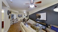 This well-designed single-floor residence offers a thoughtfully laid-out interior that balances modern style with everyday functionality. The open-concept living and dining area serves as the heart of the home, highlighted by a striking dark geometric accent wall that creates a bold focal point. Wood-look flooring flows throughout the main living spaces, and a ceiling fan overhead provides both comfort and visual interest. The living area accommodates generous seating and is complemented by an adjacent dining space, offering a seamless flow for everyday living and entertaining. The kitchen is fully equipped with rich, dark wood cabinetry extending to the ceiling for ample storage, light-colored countertops, a tile backsplash, and a full suite of stainless steel appliances including a refrigerator, range, and microwave. Track lighting illuminates the workspace efficiently. The bedroom is a calm retreat, featuring plush carpeting, a ceiling fan, and a large window that brings in natural light. The bathroom is clean and functional, offering a combined tub and shower with tile surround, a vanity with storage, and tile flooring. Together, these spaces form a cohesive, move-in-ready residence with a contemporary aesthetic and practical design throughout.