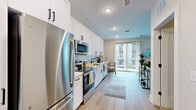 Located at 7220 Midlothian Turnpike in Richmond, VA, this thoughtfully designed one-bedroom, one-bathroom residence offers a modern and cohesive aesthetic throughout its single-floor layout. The open-concept kitchen, dining, and living area forms the heart of the home, showcasing a sleek galley-style kitchen equipped with stainless steel appliances, white shaker cabinetry with matte black hardware, a subway tile backsplash, and light quartz countertops. Light wood-tone flooring runs throughout the main living spaces, enhancing the bright and airy atmosphere. The living room benefits from generous natural light through large windows and offers access to a private balcony. The bedroom features plush carpeting, a ceiling fan, and a closet, providing a comfortable and quiet retreat. The bathroom is finished with a wood-toned vanity, white countertop, matte black fixtures, a large mirror, and a tiled walk-in shower. Additional conveniences include a dedicated laundry area within the unit. The overall design is clean and contemporary, with neutral tones and recessed lighting creating a welcoming ambiance throughout.