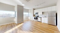 Located at 6445 America Blvd, Unit 622 in Hyattsville, MD, this one-bedroom, one-bathroom residence offers a well-designed layout that maximizes every square foot. The open-concept living, dining, and kitchen area serves as the heart of the home, bathed in natural light from multiple windows with views of the surrounding area. The kitchen features sleek white cabinetry, a white subway tile backsplash, and a full suite of stainless steel appliances, including a range, microwave, and dishwasher, all complemented by warm hardwood flooring throughout. Track lighting adds a modern touch to the living space. A light-filled hallway lined with louvered closet doors — four closets in total — provides exceptional storage and leads to the private quarters. The bedroom offers plush carpeting, neutral toned walls, and ample space for furnishings. The full bathroom is finished with large-format tile flooring and a tub-shower combination with clean white tile surround. An in-unit laundry area adds everyday convenience. The overall aesthetic is modern and neutral, with crisp white trim, soft gray walls, and an airy ambiance throughout.