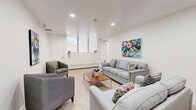 Located at 552 Birchmount Rd in Toronto's Scarborough area, this single-floor space offers a well-organized layout comprising a living room and a dining room. Throughout the space, light-toned laminate flooring provides a clean, cohesive foundation, while crisp white walls enhance the sense of brightness and openness.

The living room is a comfortable and inviting area, furnished with a grey sofa, coordinating armchairs, and a wood-top coffee table. Recessed pot lights illuminate the ceiling, supplementing the natural light that filters in through roller-shaded windows overlooking outdoor greenery. Colorful, expressive artwork decorates the walls, adding a lively artistic character to the room.

The dining area is neatly defined and features a round dark-topped table with upholstered chairs, creating an intimate setting for gatherings. Additional framed artwork adorns the walls, maintaining the vibrant aesthetic carried throughout the space.

Both rooms benefit from a consistent design sensibility — clean lines, neutral tones, and carefully chosen décor that balances functionality with visual appeal. A baseboard heating unit is visible along the perimeter, and a door provides access to an adjacent area. Overall, this space presents a tidy, well-appointed environment with a warm and welcoming ambiance.