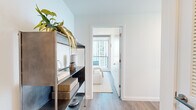 Located on South Michigan Avenue in Chicago's vibrant Grant Park corridor, this thoughtfully designed 2-bedroom, 2-bathroom residence offers a refined urban living experience. The open-concept kitchen and living area serves as the heart of the home, featuring light wood cabinetry, a sleek center island with seating, a modern pendant light fixture, and floor-to-ceiling windows that frame sweeping views of Lake Michigan and Grant Park. A dedicated dining nook with wraparound glass walls further showcases the spectacular panoramic scenery, flooding the space with natural light. The primary bedroom is a serene retreat, finished with warm wood flooring, clean white walls, and access to a dedicated closet. The bathrooms are appointed with crisp white countertops, under-mount sinks, large mirrors, and glass-enclosed walk-in showers with modern chrome fixtures. Hallways connect the spaces efficiently, and wood-look flooring flows consistently throughout, tying the interior together with a cohesive, contemporary aesthetic. The overall ambiance is calm and sophisticated, balancing neutral tones with natural textures to create a welcoming atmosphere set against one of Chicago's most iconic backdrops.