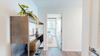 Located on South Michigan Avenue in Chicago's vibrant Grant Park corridor, this thoughtfully designed 2-bedroom, 2-bathroom residence offers a refined urban living experience. The open-concept kitchen and living area serves as the heart of the home, featuring light wood cabinetry, a sleek center island with seating, a modern pendant light fixture, and floor-to-ceiling windows that frame sweeping views of Lake Michigan and Grant Park. A dedicated dining nook with wraparound glass walls further showcases the spectacular panoramic scenery, flooding the space with natural light. The primary bedroom is a serene retreat, finished with warm wood flooring, clean white walls, and access to a dedicated closet. The bathrooms are appointed with crisp white countertops, under-mount sinks, large mirrors, and glass-enclosed walk-in showers with modern chrome fixtures. Hallways connect the spaces efficiently, and wood-look flooring flows consistently throughout, tying the interior together with a cohesive, contemporary aesthetic. The overall ambiance is calm and sophisticated, balancing neutral tones with natural textures to create a welcoming atmosphere set against one of Chicago's most iconic backdrops.