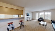 Located at 4300 Collegiate Way in Mount Pleasant, Michigan, this well-appointed two-bedroom, three-bathroom unit offers a practical and comfortable single-floor layout. The open living room is bright and welcoming, featuring plush carpeting, multiple windows, and a glass door that floods the space with natural light and provides access to an outdoor area. A pass-through counter with bar seating connects the living area to the kitchen, which is equipped with light wood cabinetry, laminate countertops, and a convenient in-unit laundry area with a washer and dryer tucked neatly alongside. The kitchen and laundry zone feature durable hardwood-style flooring for easy maintenance. Both bedrooms are carpeted and offer mirrored sliding closet doors, natural light from exterior windows, and comfortable proportions. The primary bedroom provides a generous layout with ample closet space. Three full bathrooms each include a single-sink vanity with light wood cabinetry, a tub/shower combination, and hardwood-style flooring. Two additional office spaces provide flexibility for study or remote work. The unit's neutral color palette and clean lines create a functional and adaptable living environment suited for a variety of lifestyles.